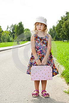 Girl with suitcase standing on road