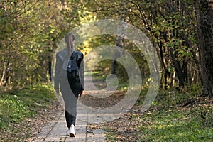 Lonely girl is walking along the alley of the park. Back view. Alone with myself