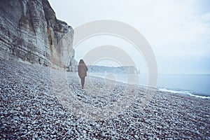 A lonely girl walks along the ocean