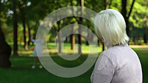 Lonely grandmother remembering her happy childhood, sitting in park alone