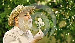 Lonely grandpa blowing dandelion seeds in park. Mental health. Peace of mind. Peacefulness. Tranquility and serenity photo