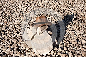 Lonely grave in a rocky desert with a cowboy hat