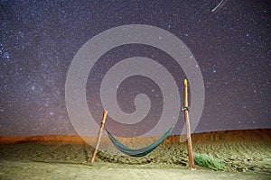 Lonely hammock next to dunes on Sahara desert with amazing starry sky above, Morocco