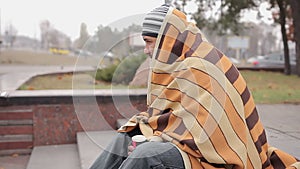 Lonely homeless man covered with shabby blanket feeling cold, asking for money