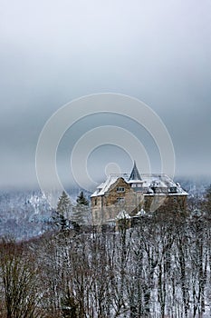 A lonely house stands on a hill in the middle of a forest