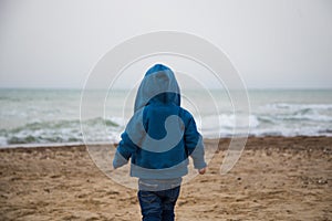 Lonely little boy on the beach rear view