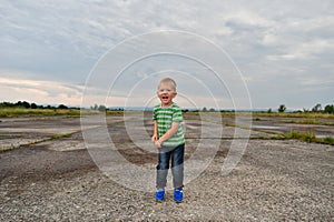 Lonely little boy stands in the field on the landing strip