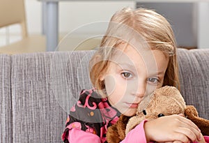 Lonely little girl sitting sadly on sofa photo