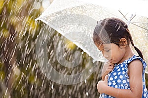 Lonely little girl with umbrella in rain
