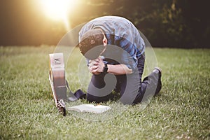 Lonely male praying on his knees next to a guitar and the Holy Bible