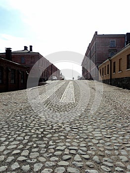 A lonely man in the cobblestone street in the sun