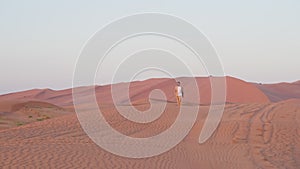 lonely man in dunes of desert in sunset or sunrise time, general shot, lost in edge of world