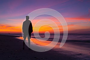 Lonely man on the empty beach at dramatic sunset. Cape Cod, USA