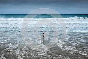 Lonely man entering the water at overcast beach