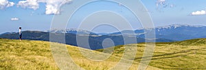 Lonely man hiker standing on a wide hill enjoing mountain view