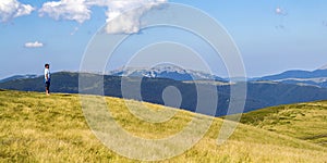 Lonely man hiker standing on a wide hill enjoing mountain view