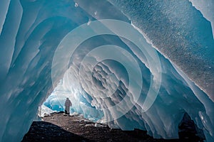 Lonely man in large ice cave in snow journey.