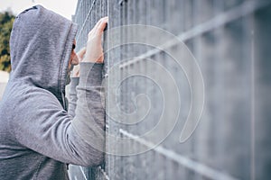 Lonely Man Leaning against Fence