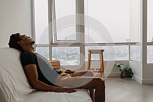 Lonely man lie on sofa desperately in his apartment.