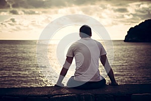 Lonely man looking with hope at horizon with sunlight during sunset with effect of light at the end of tunnel