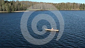 A lonely man oaring the boat at middle of lake