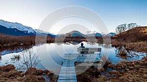 A lonely man sitting on a bench in Glenorchy, New Zealand