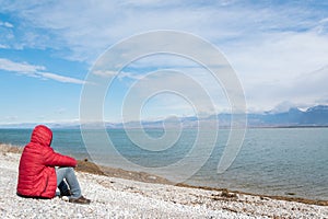 Lonely man sitting on the lakeshore, admiring the nature. Unrecognisable person