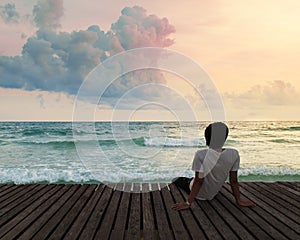 Lonely Man sitting in wooden dock pier in sea beach with twilight sky in sunset time and think concentrate