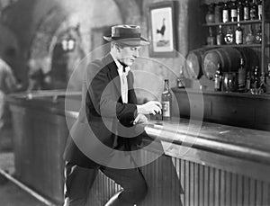 Lonely man standing at a bar counter with a drink