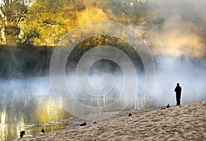 Lonely man standing soul searching on bank foggy misty river