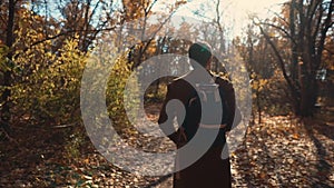 Lonely man is strolling in woodland in sunny day in autumn, back view