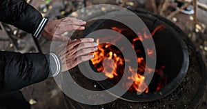 Lonely man tourist or homeless person warms hands over fire at night