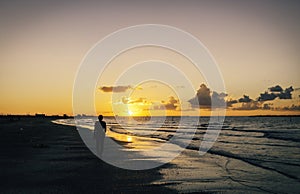 Lonely man walking on the beach at sunset