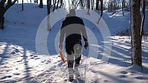 A Lonely Man walks through Snowy Forest with a Sled in His Hands. Slow motion