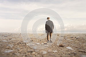 Lonely man walks towards an unknown destination in a desert