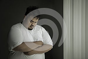 Lonely obese man looks sad at home