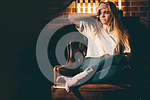 Lonely, offended, upset girl sitting on a chair in a dark room