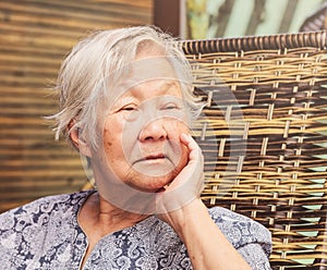 Lonely old lady seated at home, with the hand on chin with a sad