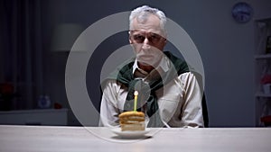 Lonely old man celebrating birthday alone, forgotten by children and relatives