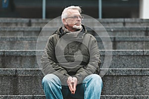 Lonely old man. A gray-haired man with wrinkles sits outside, sad. Lost a loved one, negative thoughts and depression