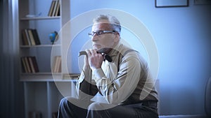 Lonely old man leaning on walking stick, dreaming, remembering youth, nostalgia photo