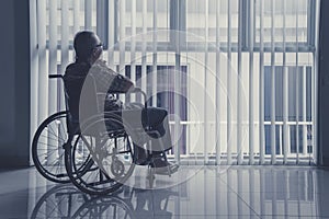 Lonely old man sitting on wheelchair at home