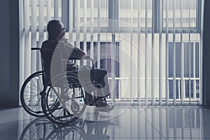 Lonely old man sitting on wheelchair at home photo