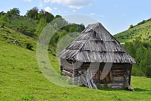 Lonely old wood house on a mountain hill against cloudy sky