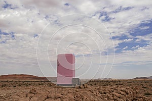 A lonely pink refrigerator stands in the Namib desert against the backdrop of a cloudy sky