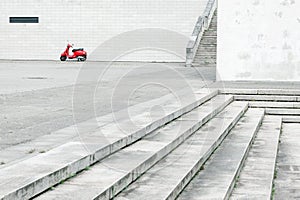 Lonely red scooter against white wall in urban environment