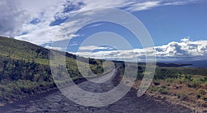 Lonely and remote rugged road, Piilani Hwy past Hana around south of Maui with Haleakala mountain, ocean and clouds in background