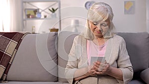 Lonely retired woman looking at photo in hands, separation hopelessness, sadness