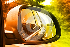 Lonely road seen through rear side mirror. Sky and trees landscape Reflect in Mirror of Car During the Car Moving concept. Travel