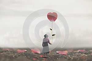 Lonely romantic woman holds a giant petal made to heart photo